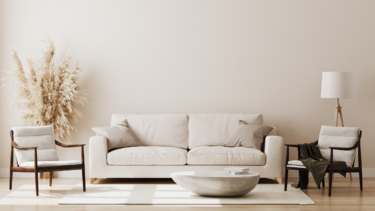 Minimalist living room featuring a neutral-toned sofa, two accent chairs, a modern coffee table, and natural decor elements like pampas grass.
