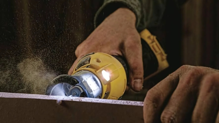 A person using a yellow power tool with a cutting wheel, emitting sparks and dust while cutting a surface.
