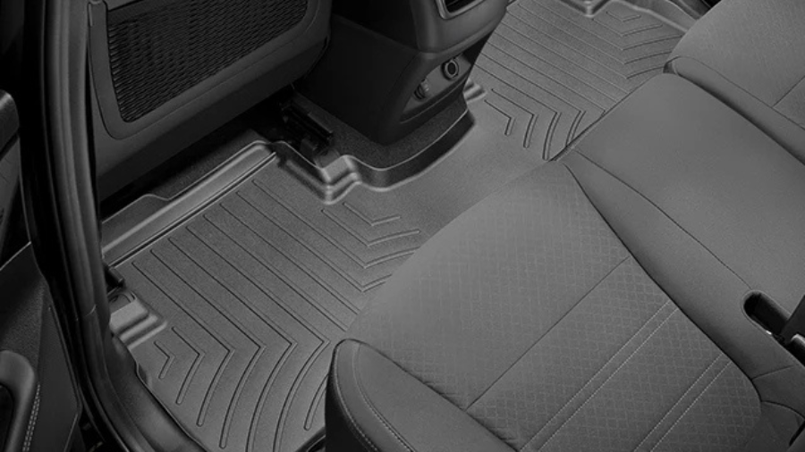 Close-up of black all-weather floor mats installed in the rear passenger area of a car.