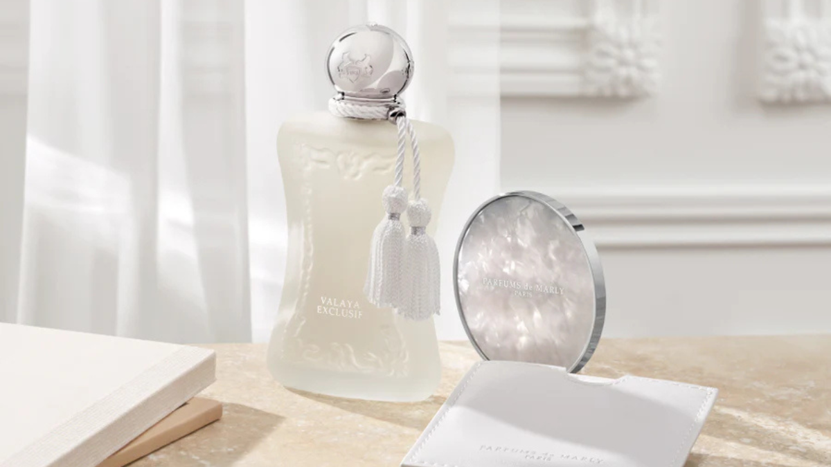 A luxurious perfume bottle with intricate detailing, accompanied by a sleek compact and pouch, elegantly arranged on a marble surface.