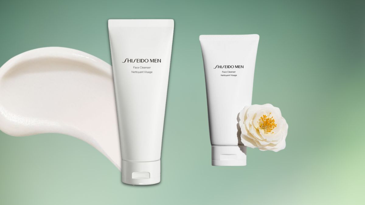 Two white tubes of Shiseido Men Face Cleanser are displayed on a soft green background, with a cream texture and a white flower beside them.