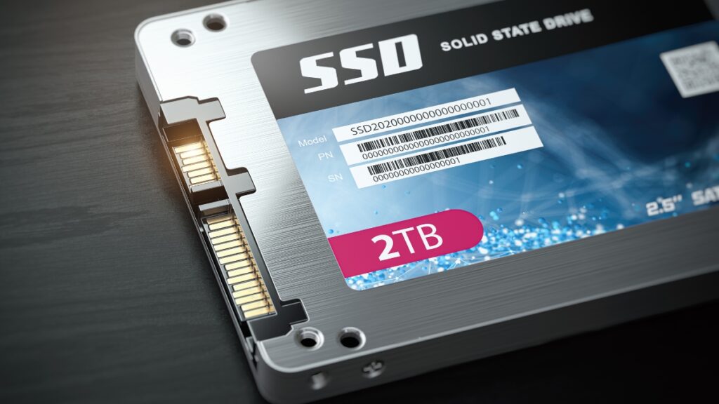 A close-up of a 2TB solid-state drive (SSD) with a silver casing and SATA connector, placed on a dark surface.
