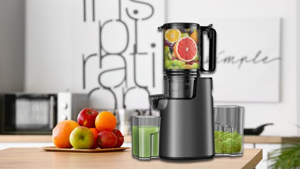 A black juicer from top Amazon deals is filled with fresh fruits on a kitchen counter next to a plate of apples and oranges, with two glasses of juice beside it.