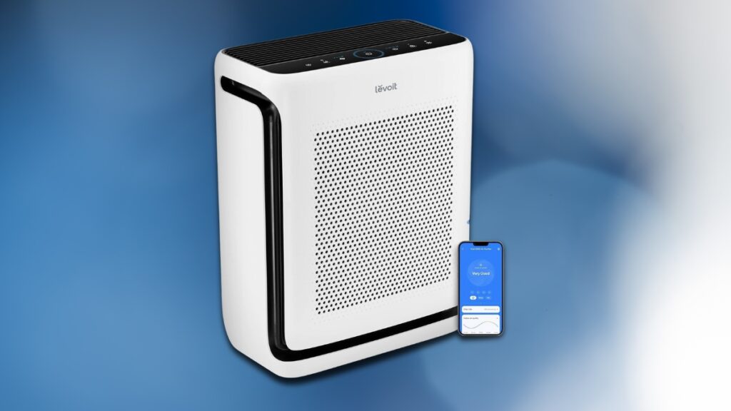 A white Levoit air purifier with a sleek design is displayed next to a smartphone showing its air quality monitoring app.