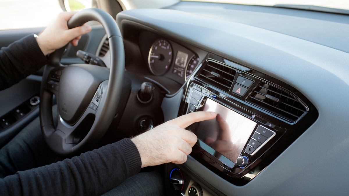 Driver using a car's Android 13 touchscreen stereo to access navigation and media controls.
