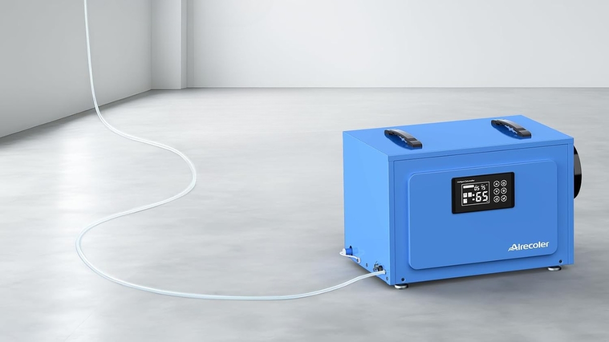 Blue Airecoler commercial dehumidifier with pump shown on a clean concrete floor, connected to a long drainage hose.