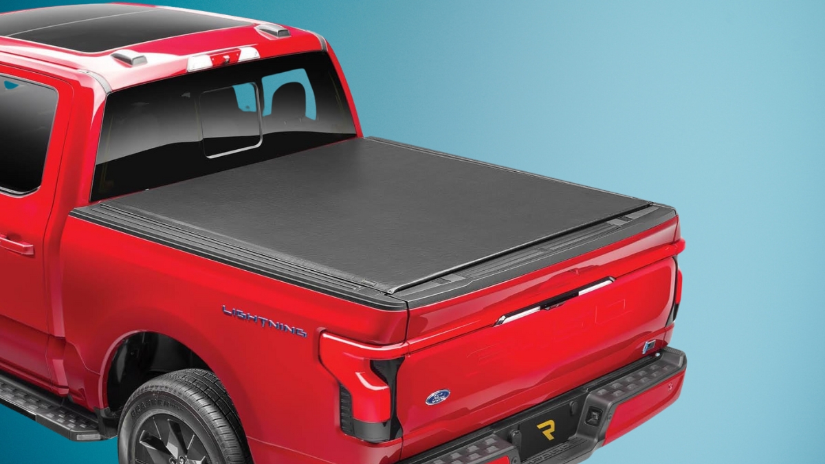 Red Ford F-150 Lightning with a soft roll up tonneau cover installed over the truck bed.